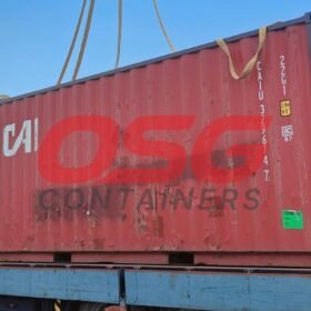 A red shipping container is being loaded onto a truck.