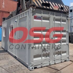 A gray shipping container office with other containers stacked around.
