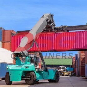 A crane lifts a pink shipping container at a busy port.
