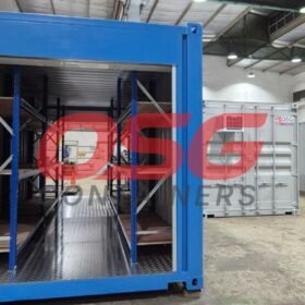 Blue shipping container with shelves inside, in a warehouse.