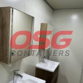 Modern bathroom with two sinks, mirror, and remote control.