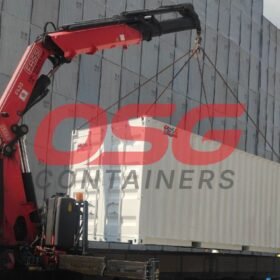 Crane lifting a shipping container onto a truck.