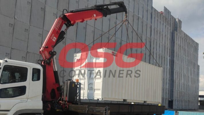 Crane lifting a shipping container onto a truck.