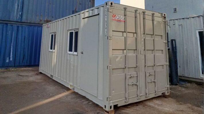 A light gray shipping container office with windows and a door.