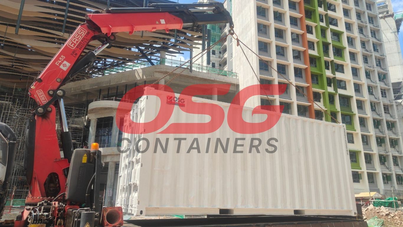 Crane lifts a shipping container at a construction site.