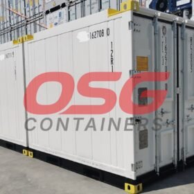 White shipping containers stacked in a yard with a logo.