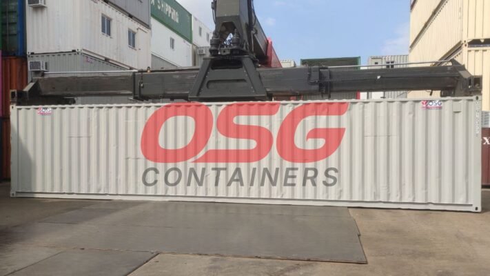 A crane lifts a white shipping container with OSG logo.