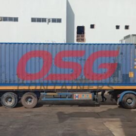 A blue shipping container on a truck with OSG logo.
